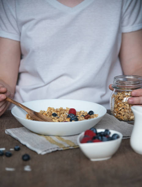 istock hand pours muesli with berries into a plate  on woodet table 1193974882