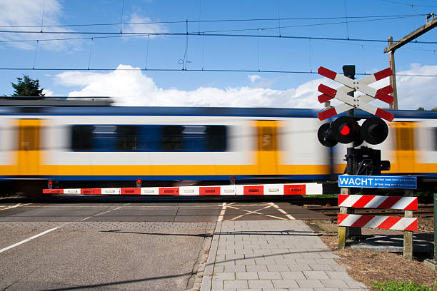 Motion-blurred train passing by a railroad crossing High speed train passing a railway crossing intercity train photos stock pictures, royalty-free photos & images