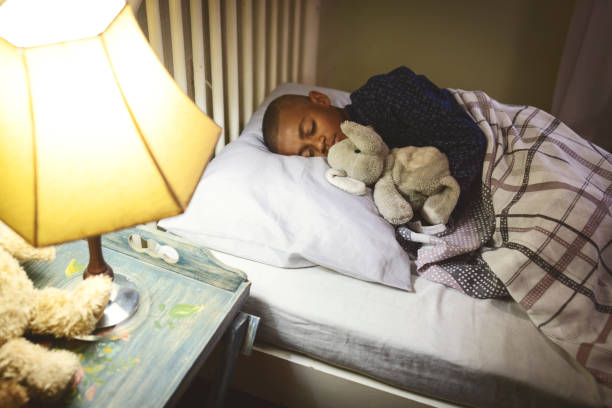 istock Cute boy sleeping on the bed embracing a teddy bear 1193976151