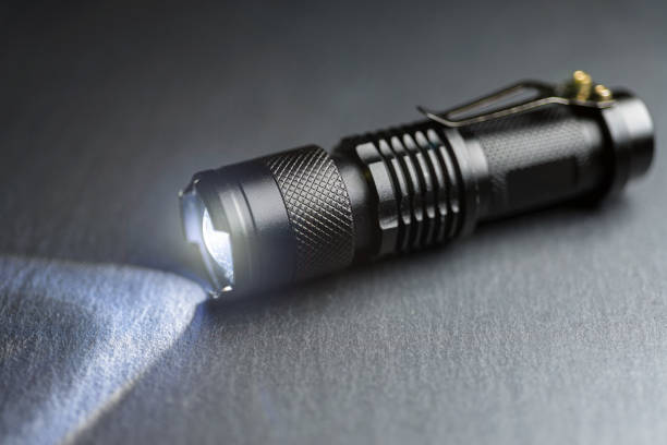 istock Tactical waterproof flashlight. LED flashlight shines on the table in smoke. 1193976931