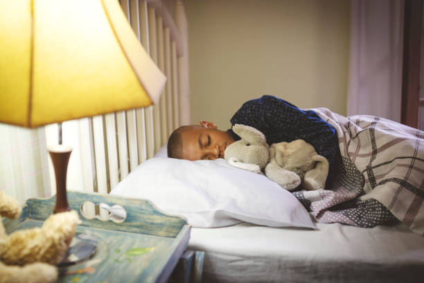 istock Cute boy sleeping on the bed embracing a teddy bear 1193976937
