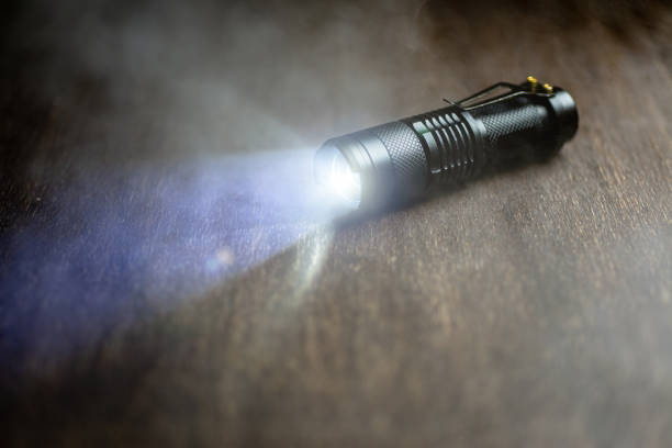 istock Tactical waterproof flashlight. LED flashlight shines on the table in smoke. 1193977088