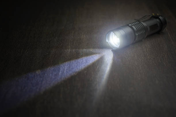 istock Tactical waterproof flashlight. LED flashlight shines on the table in smoke. 1193977120