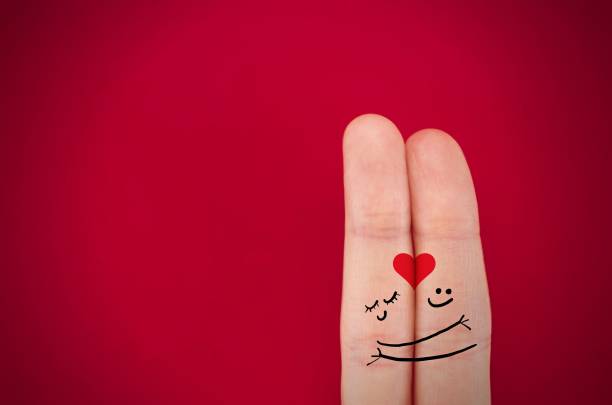 fingers coupled together with a painted heart, a cheerful smile, smileys, emojis, isolated on red background, the symbol of love, relationships
