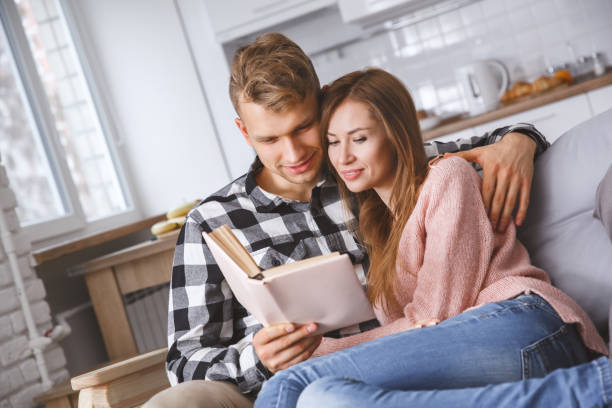 istock Young couple together at home love concept reading book 1193990842