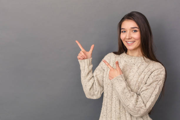 istock Copy Space for Text or Product. Young woman in sweater standing studio isolated on grey pointing aside smiling happy 1193990885