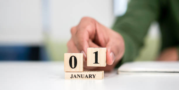 close up employee man hand put number 1 of cube shape wood to make calendar date January at office desk for the new day in first date of the year countdown concept close up employee man hand put number 1 of cube shape wood to make calendar date January at office desk for the new day in first date of the year countdown concept new years day photos stock pictures, royalty-free photos & images