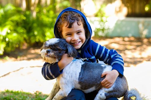 Cute boy enjoying the outdoors in a home yard setting with his dog.