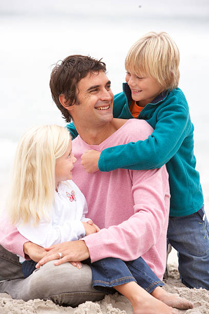 istock Father And Children Sitting On Winter Beach 119399791