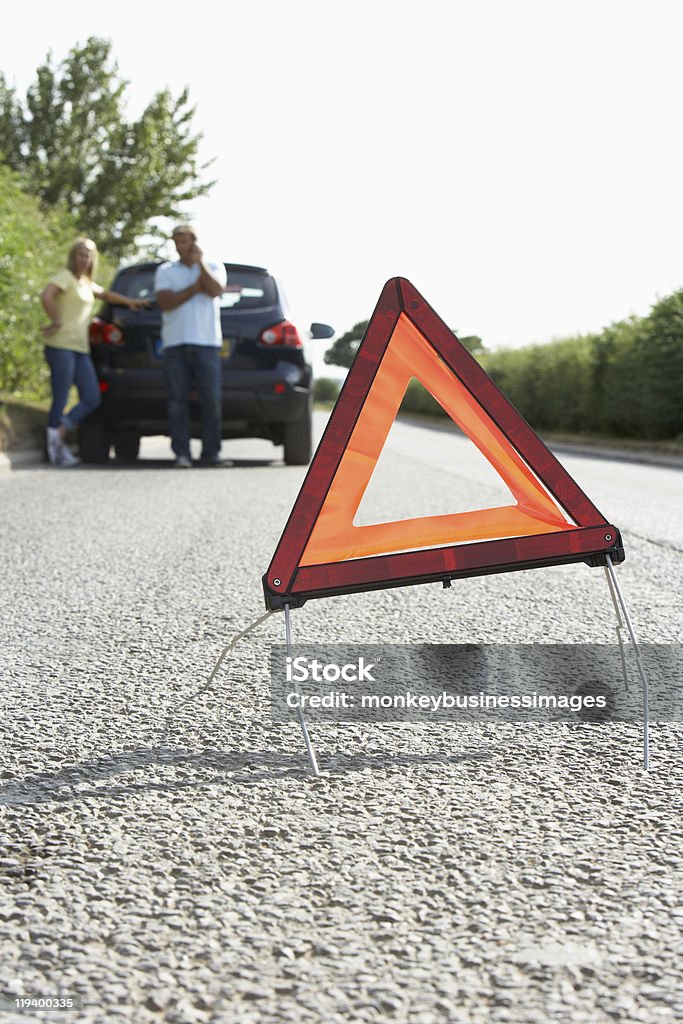 Paar gebrochen Down auf Landstraße mit Hazard Warning Sign - Lizenzfrei Am Telefon Stock-Foto