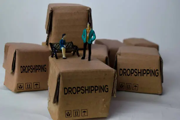 Miniature businessman talking on Boxes with text Dropshipping isolated white bakground
