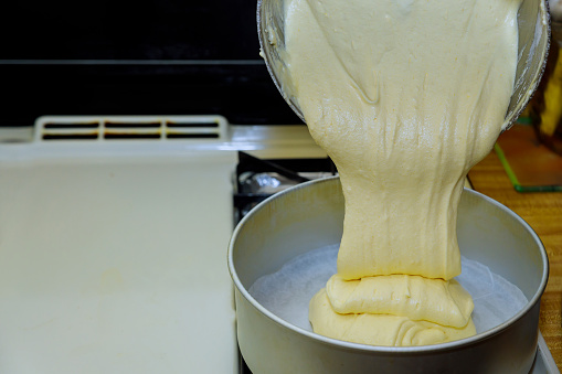 Pouring fluffy dough into round baking pan. Making sponge cake.