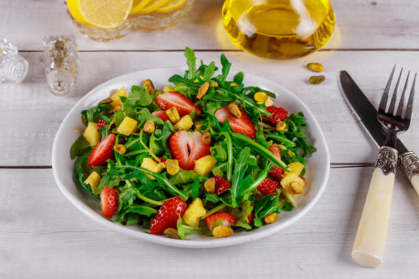 istock Fresh salad with arugula, strawberries, pineapple and pistachios served on white plate on rustic wooden table. 1194016474