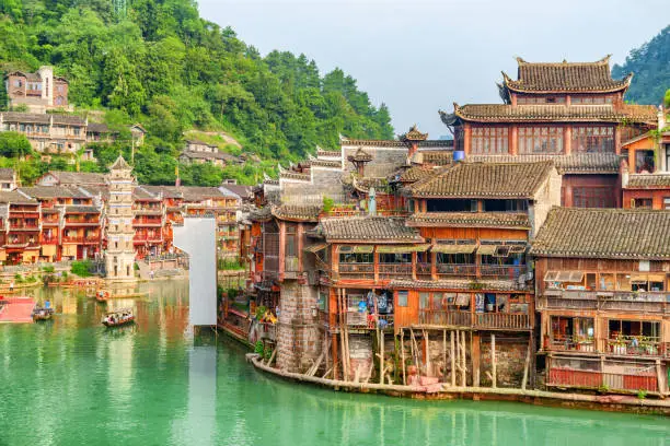 Awesome view of the Tuojiang River (Tuo Jiang River) and old traditional Chinese wooden riverside houses in Phoenix Ancient Town (Fenghuang County), China. The Wanming Pagoda is visible at left.