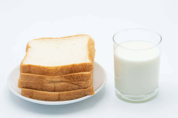 A glass of milk with a bread on a white plate isolate on white background