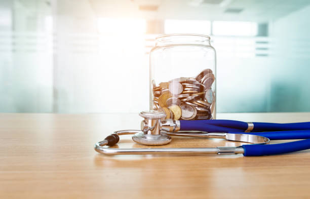 stetoscopio e vasetto di monete sul tavolo - currency stethoscope healthcare and medicine savings foto e immagini stock