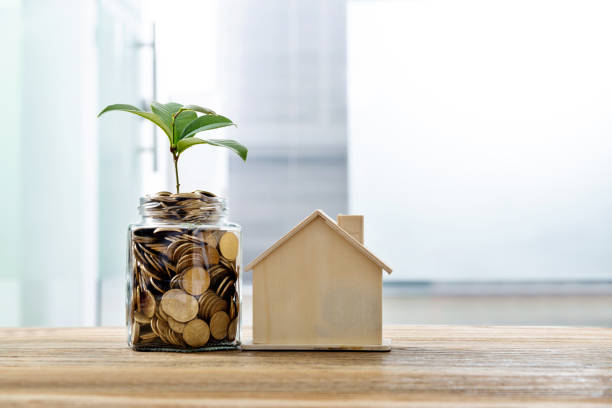 istock Glass coin jar and house model on the table 1194029998