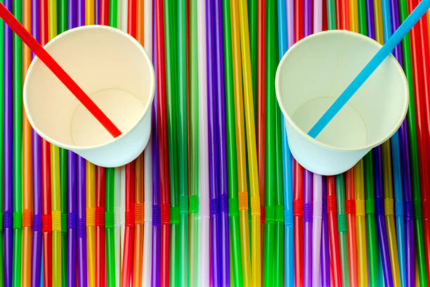 drinking straws. abstract background with many multi colored plastic tubules for juice or cocktail, single-use disposable. and two empty white paper cups in middle.top flat view. - drinking straw plastic design in a row imagens e fotografias de stock