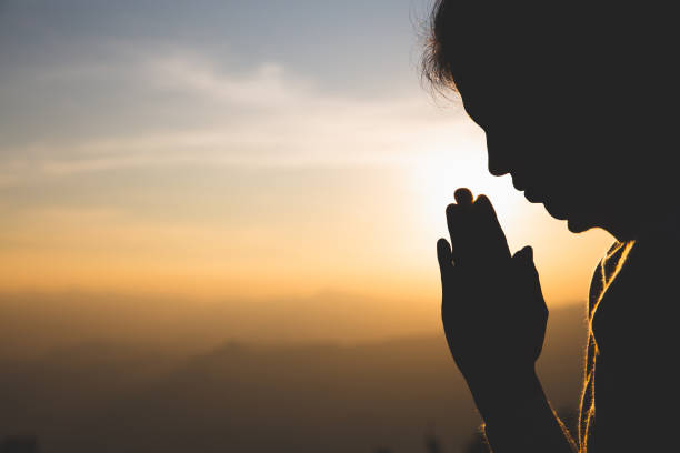 silhouette d'une femme priant des mains avec la foi dans la religion et la croyance en dieu sur le fond de lever de soleil de matin.  namaste ou namaskar geste de mains, respect de salaire, position de prière. - penance photos et images de collection