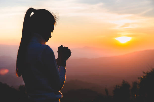 woman praying in the morning on the sunrise background. christianity concept. pray background. faith hope love concept. - cross cross shape christianity hope imagens e fotografias de stock