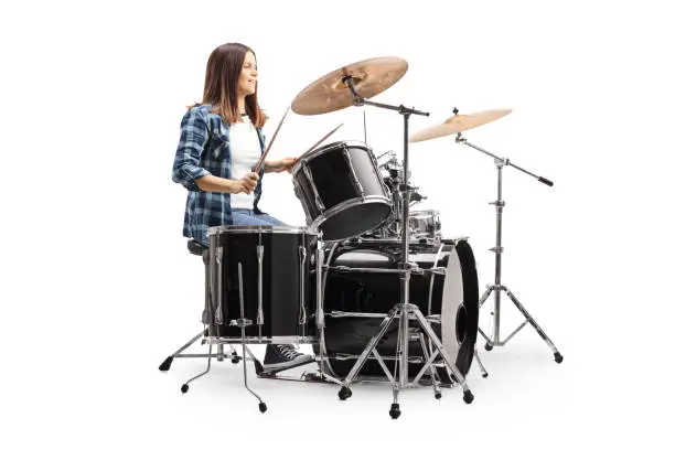 Young female drummer playing a drum set isolated on white background