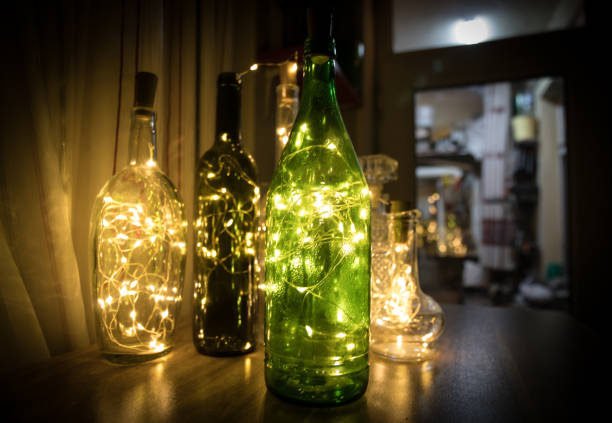 Lights garland in a glass bottle on a dark background. Warm interior design