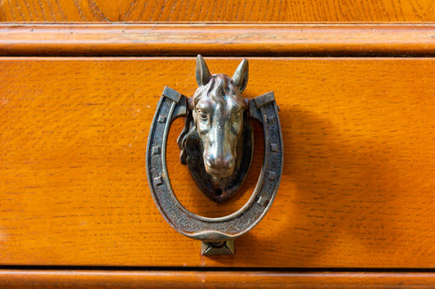 very old antique metal door knocker in form of a horse's head, with a horseshoe in its mouth