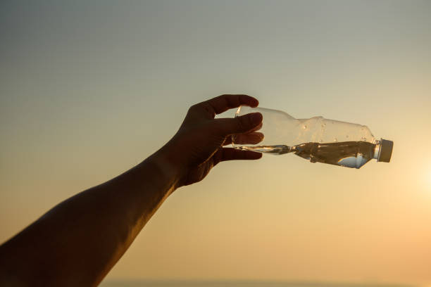 istock Man hand holding crystal clear water bottle in the sunset 1194050031