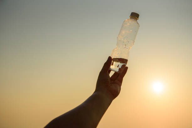 istock Man hand holding crystal clear water bottle in the sunset 1194050035