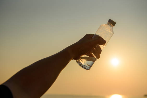 istock Man hand holding crystal clear water bottle in the sunset 1194050036