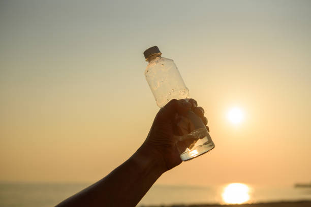 istock Man hand holding crystal clear water bottle in the sunset 1194050043