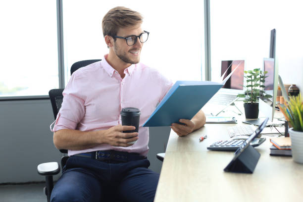 istock Young man is working with papers while sitting in the office 1194052239