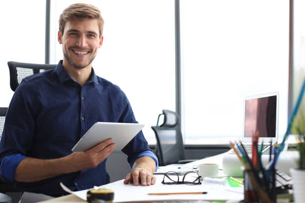 istock Young modern business man working using digital tablet while sitting in the office. 1194055012