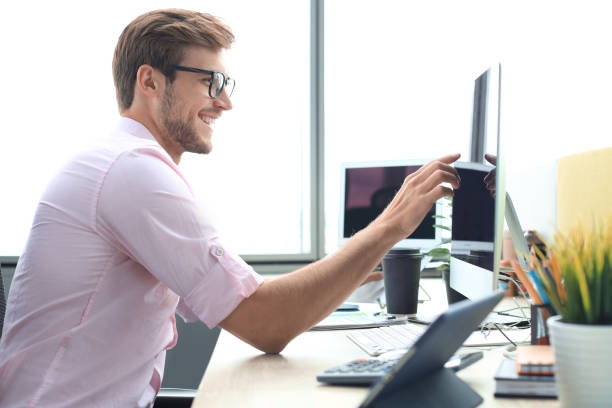 istock Thoughtful young business man in shirt working using computer while standing in the office. 1194055082