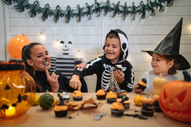 Playful family on Halloween night Small brother and sister playing around with their mother in their home during Halloween night halloween cupcake stock pictures, royalty-free photos & images