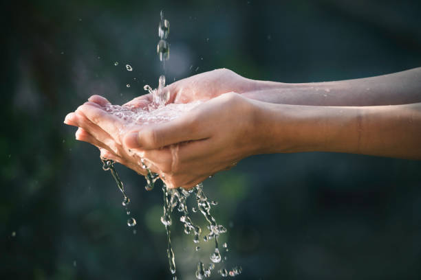 fluxo de água do closeup à mão das mulheres para o conceito da natureza no fundo do jardim. - human hand water environment nature - fotografias e filmes do acervo