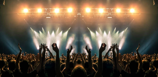 palco de concertos, as pessoas são visíveis acenando e batendo palmas, silhuetas são visíveis - crowd music festival audience spectator - fotografias e filmes do acervo
