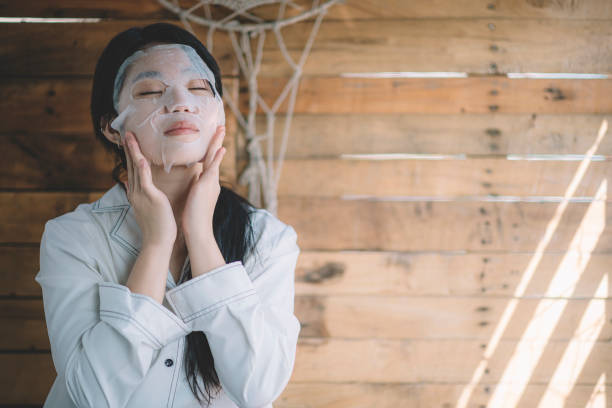 seorang gadis remaja cina asia meletakkan topeng lembaran wajah di wajahnya - sheet mask potret stok, foto, & gambar bebas royalti