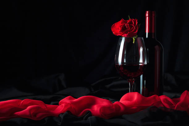 istock Red wine and red rose on black background. 1194062514