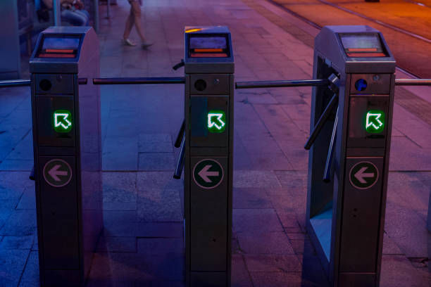 Three turnstiles of a tram station by night.