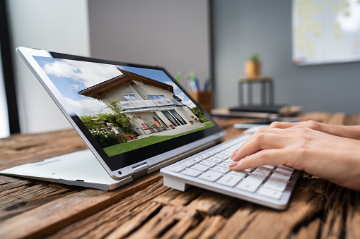 Woman Selecting New House On Laptop Computer