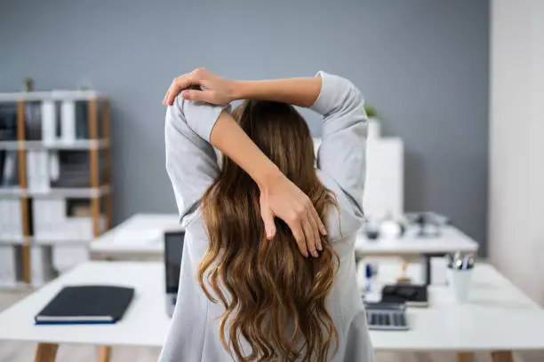 Close-up Of A Young Businesswoman Stretching Her Arms At Workplace