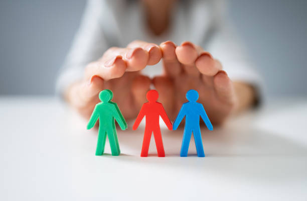 istock Person Protecting Multicolored Pawns 1194077300