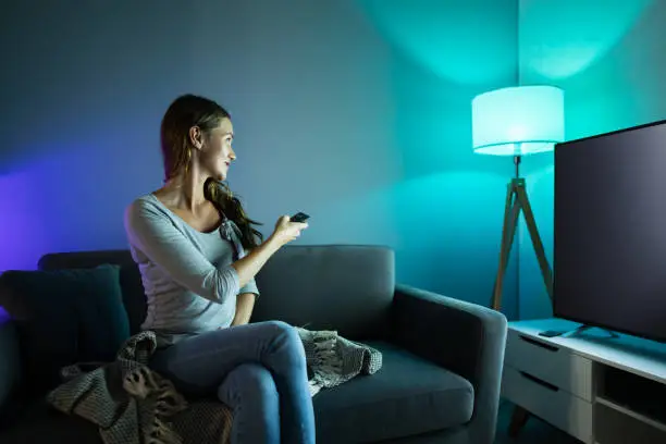 Happy Smiling Woman Controlling Electric Lamp With Mobile Phone At Home