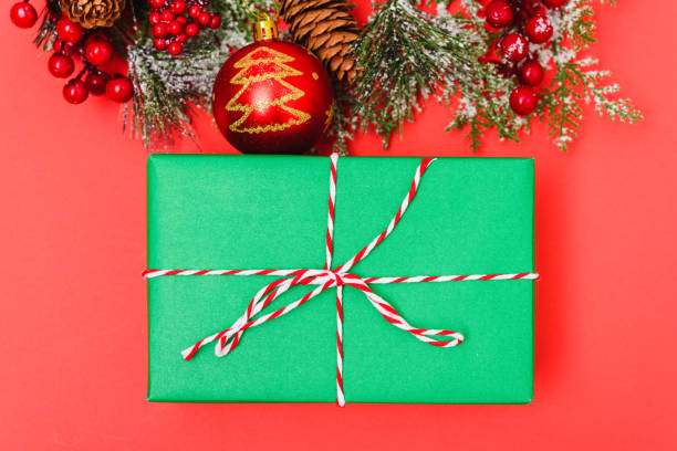 istock Christmas green gift box and decorations, fir tree branches on red background 1194080744
