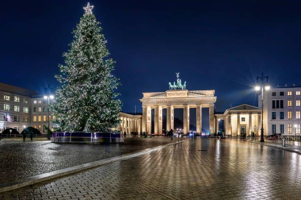 vista nocturna a la puerta de brandenburgo en berlín, alemania, con un árbol de navidad iluminado en frente - brandenburg gate berlin germany germany night fotografías e imágenes de stock