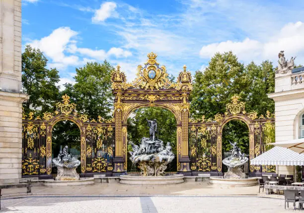The fountain of Neptune in the Rococo style and the gilded wrought iron portico in the north-west corner of the place Stanislas in Nancy, France.