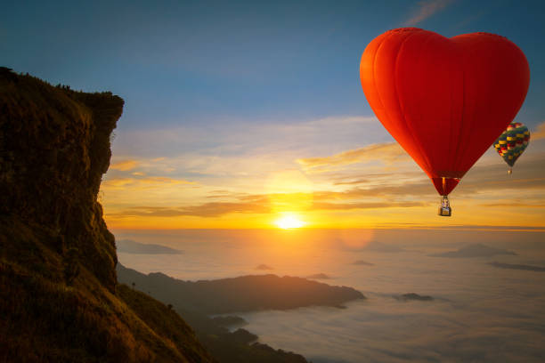 el globo aerostático en forma de corazón sobrevuela el parque nacional de la montaña phucheefah - hill dusk sunset heat haze fotografías e imágenes de stock