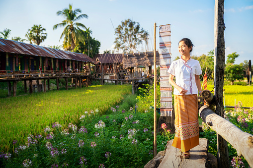 Thai girl walk on paddy and rice farm in lamduan woven cloth coffee shop, Pua, Nan, Thailand