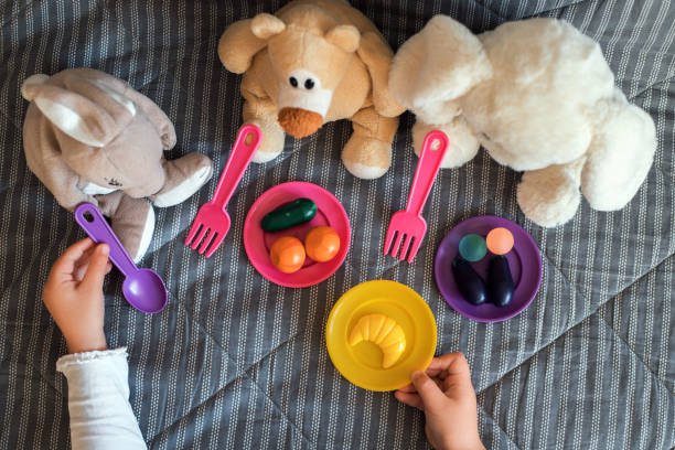 petit enfant alimentant ses jouets en peluche à la maison. - stuffed animal photos photos et images de collection